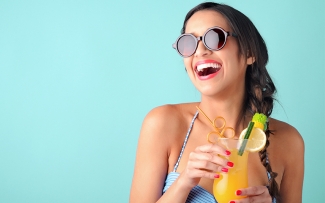 woman smiling with a tropical drink and sunglasses summer