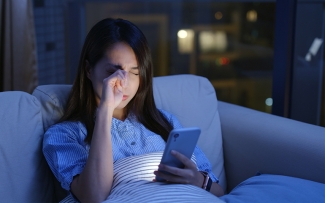 woman looking at phone at night tired eyes